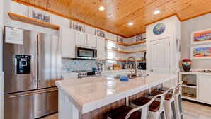 A modern kitchen with stainless steel appliances, a central island with bar stools, and wooden ceiling. - Gorgeous, pet friendly, coastal cottage within walking distance to the restauran (Port Aransas)