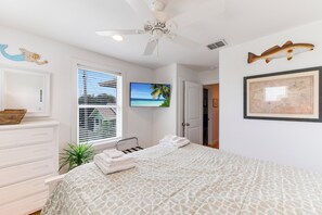 Une chambre à coucher avec un lit, un ventilateur de plafond, une télévision, une carte et un décor à thème marin.