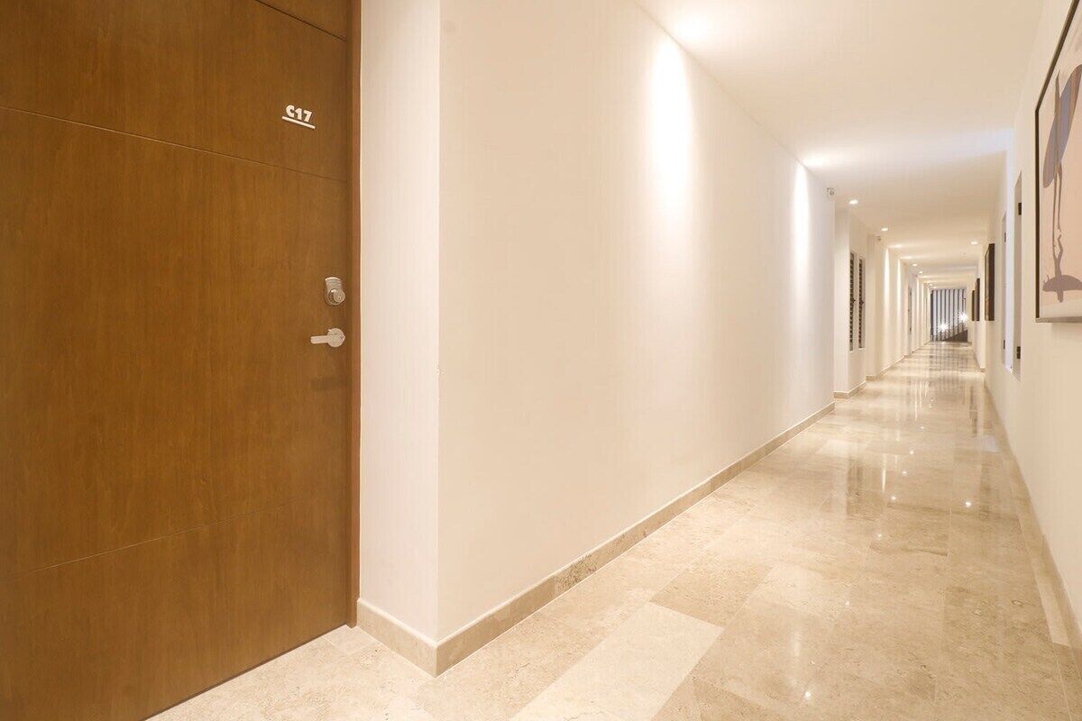 A long, well-lit hallway with a wooden door labeled "S17" and a marble floor.