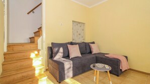 A living room with a grey sectional sofa, a small round table, and a staircase. - Ines in Barban  - Haus für 4-5 Personen (Barban)