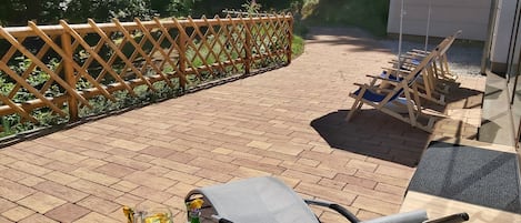Un patio al aire libre con una mesa, sillas, un paraguas de Pepsi y una valla de madera.