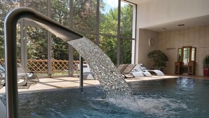 Piscina con fuente de agua, sillas de descanso y ventanas amplias.