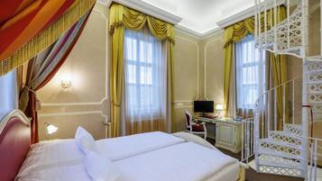 A hotel room with a bed, a desk, a computer, and a staircase.