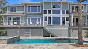 A two-story house with a swimming pool, a covered patio, and a staircase leading to the upper floor.