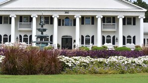 A large white building with a central entrance, columns, and a fountain in the foreground. - Close to Beach Brunswick Plantation Condo 2302M with 27 Hole Golf Course Onsite by RedAwning (Calabash)