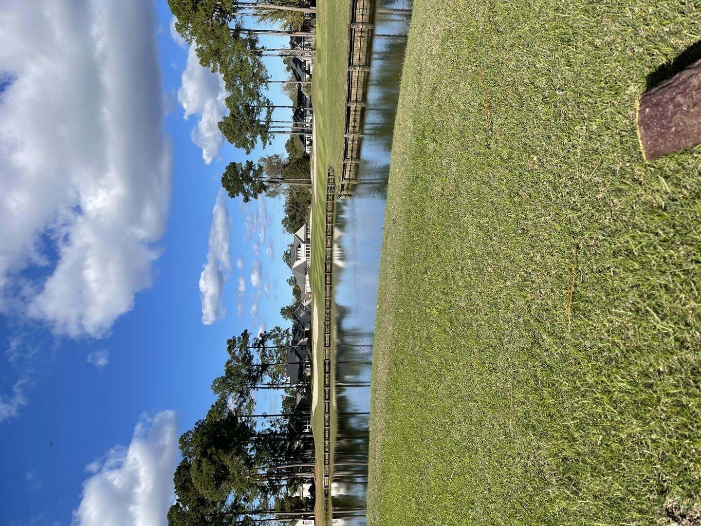 Ein Golfplatz mit blauem Himmel und einem Gewässer.