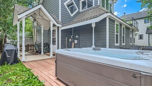 A hot tub in a backyard with a wooden deck, a covered patio, and a fence. - The Powder Chalet 3 Bedroom Home by RedAwning (Breckenridge)
