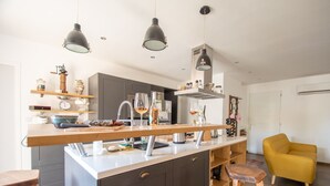 Una cocina moderna con una isla central, taburetes de bar e iluminación colgante.