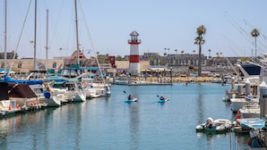 A marina with boats, a lighthouse, and a building with a red roof. - Tranquil NCV Beach Condo with Lush Gardens & Ocean Glimpses! (Oceanside)