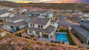 Zona residencial com casas modernas, piscina e paisagem montanhosa ao fundo.