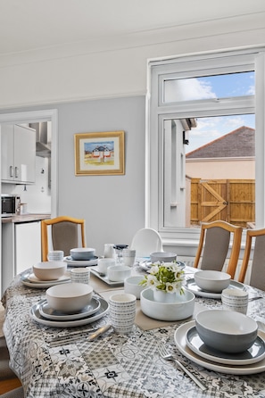 Enjoy meals in this dining area with a table set for a meal, featuring a vase with flowers and a framed picture on the wall.