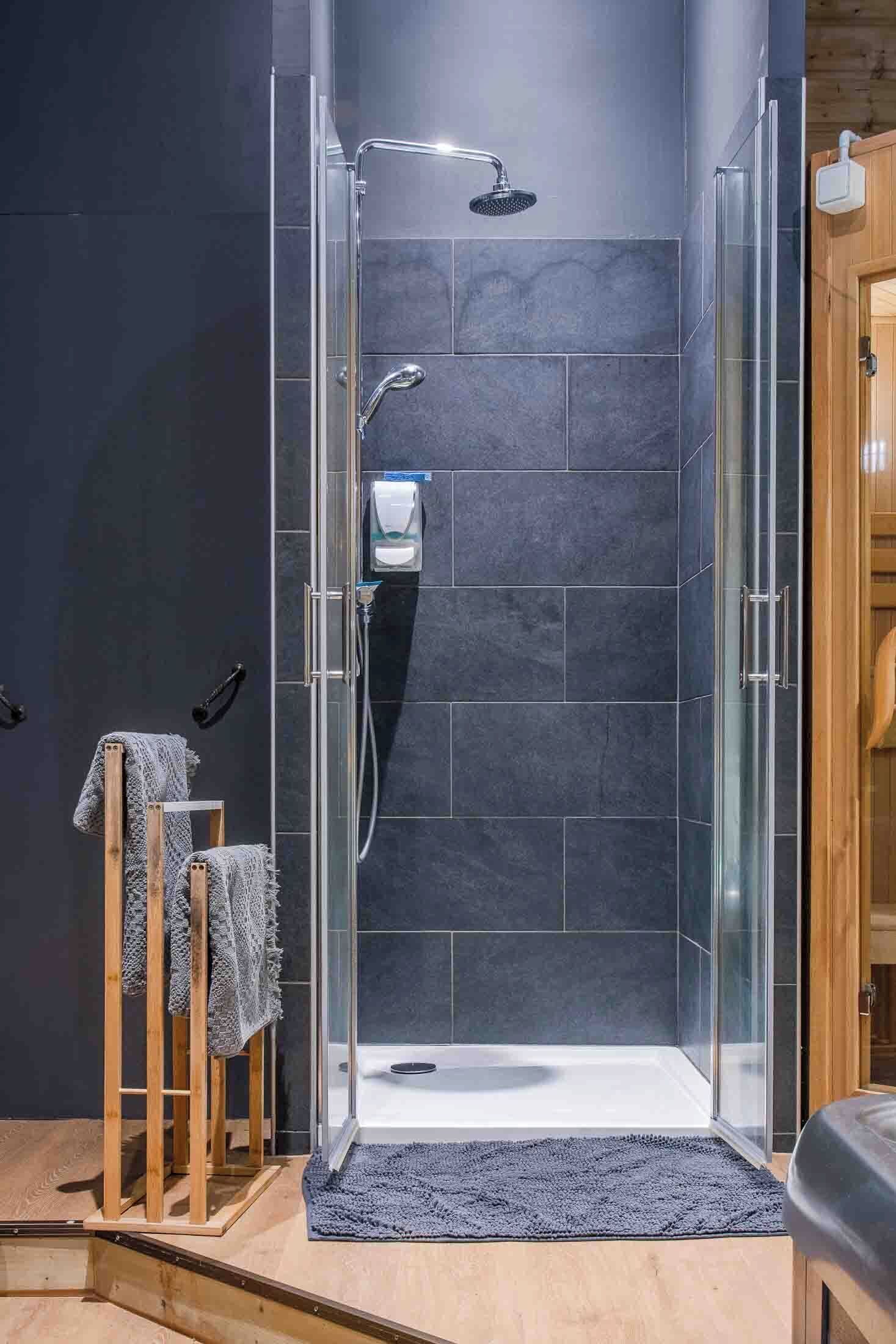 A modern shower room with a glass enclosure, a handheld showerhead, and a handheld faucet.