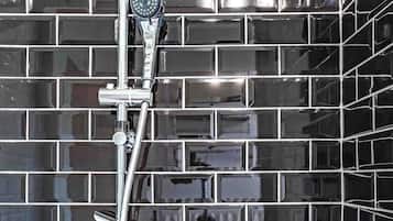 A shower with chrome fixtures against a tiled wall.