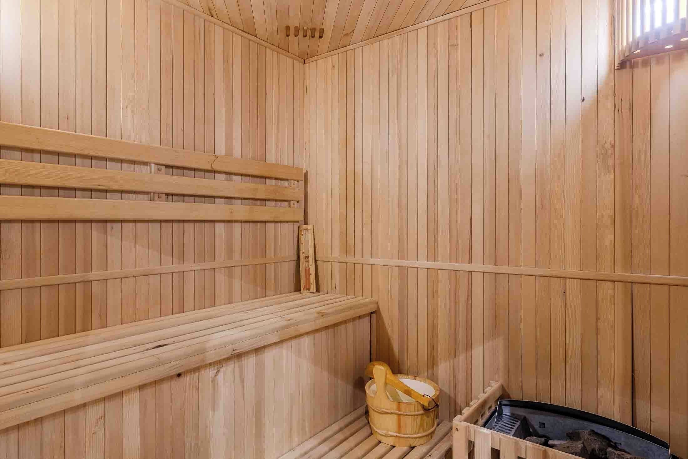 Una sauna de madera con bancos y un balde de madera.