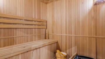 Una sauna de madera con bancos y un balde de madera.