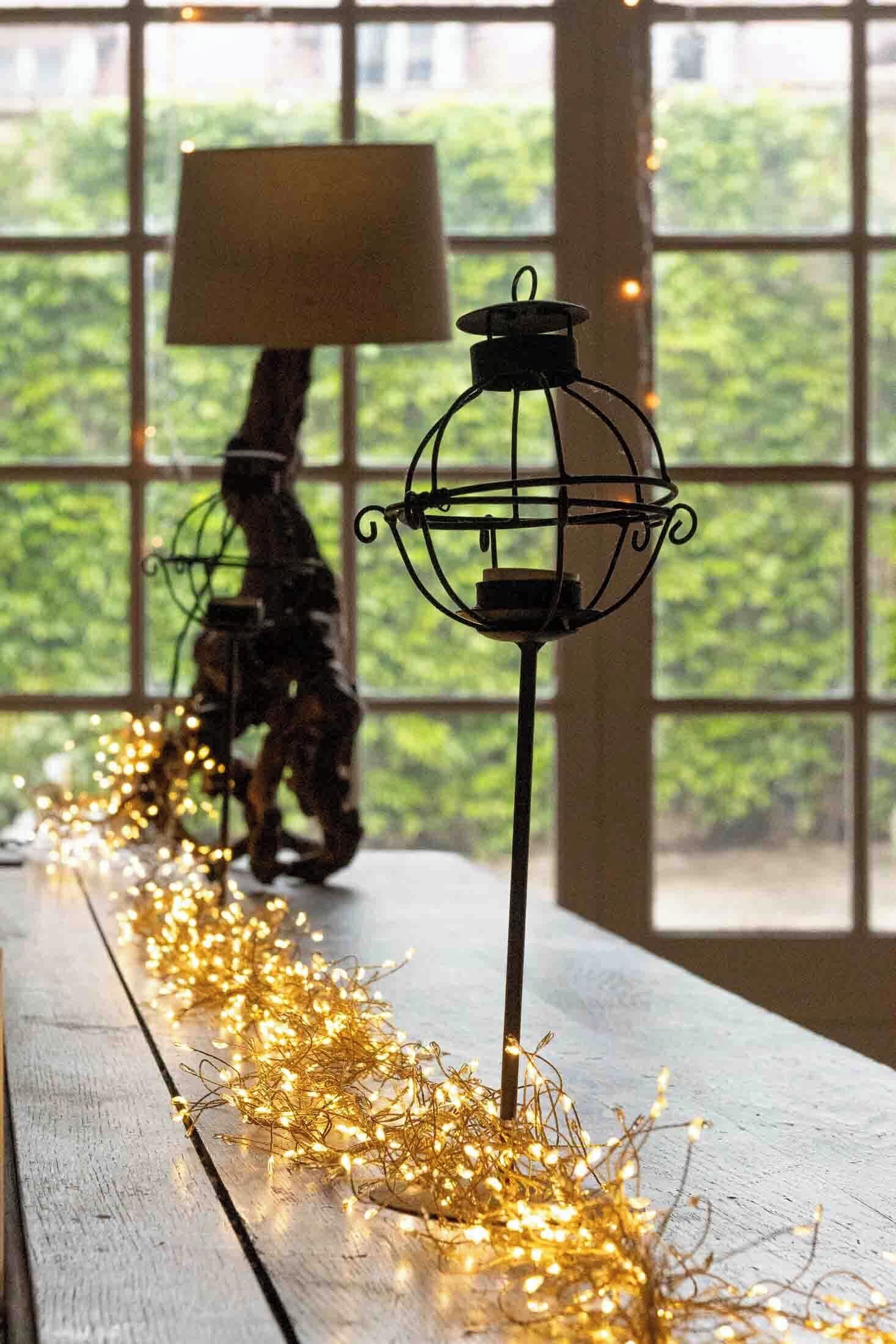 Une table ornée d’une lampe et d’un objet décoratif, le tout entouré de guirlandes lumineuses.
