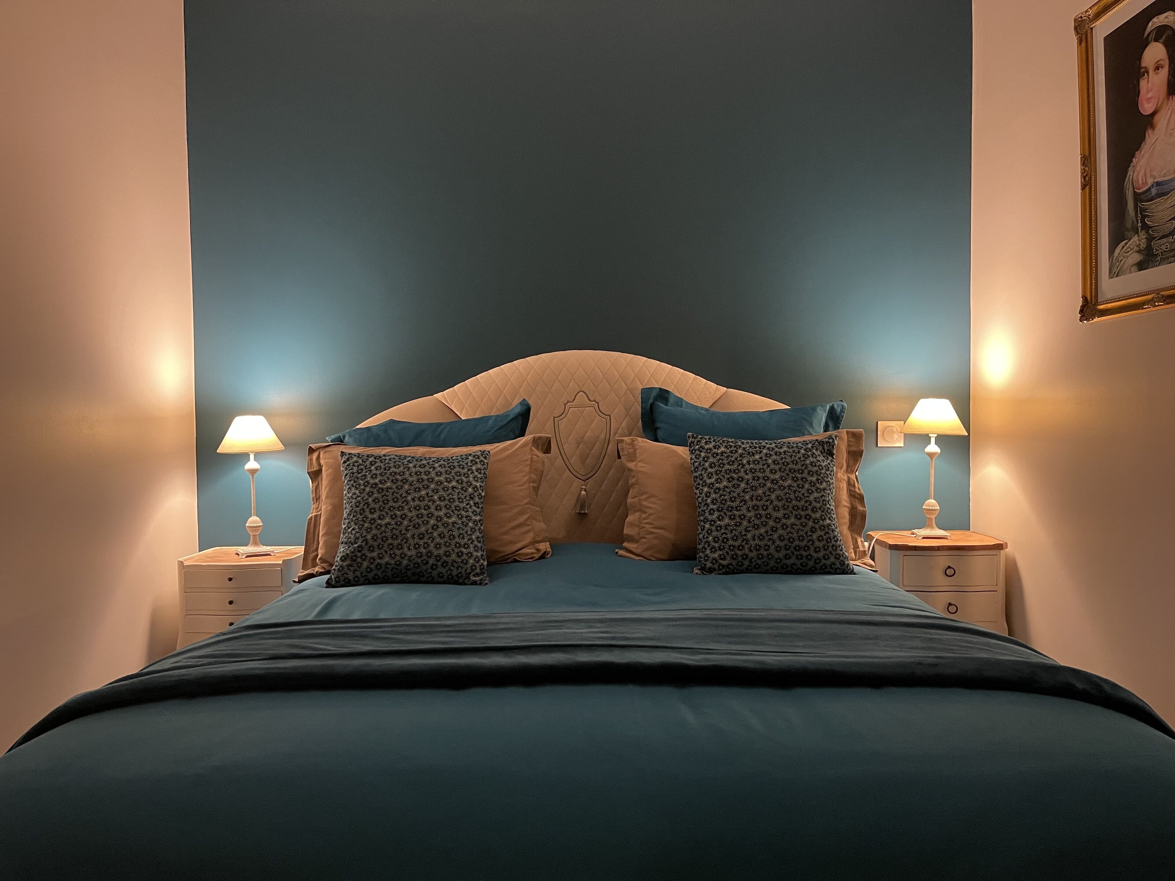Un dormitorio con una cama grande, dos mesitas de noche con lámparas y un cabecero.