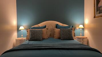 Un dormitorio con una cama grande, dos mesitas de noche con lámparas y un cabecero.
