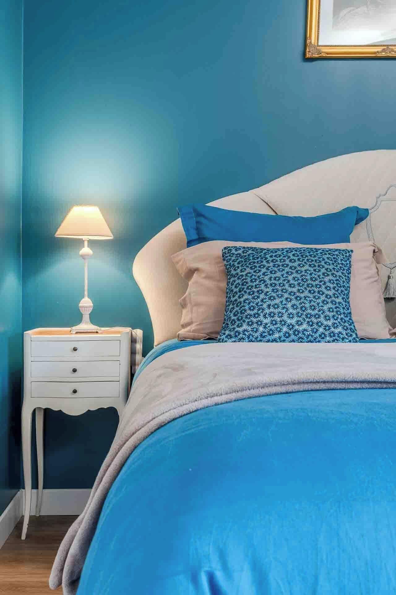 Une chambre à coucher avec un lit, une table de chevet et une lampe.