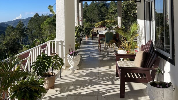 A covered outdoor area with a wooden bench, potted plants, and a view of the mountains. - Starlight Chalet (Silver Hill Gap)