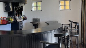 A bar area with a curved counter, bar stools, and two arched windows. - Starlight Chalet (Silver Hill Gap)