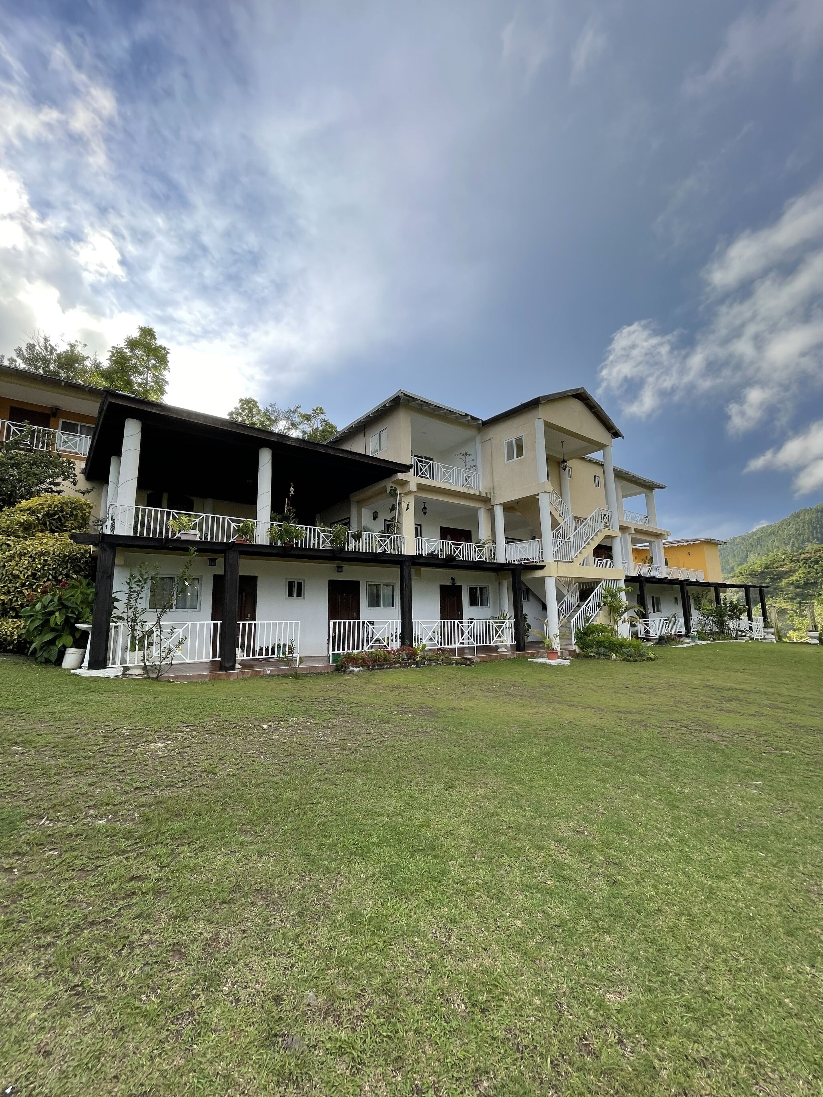 A two-story building with a covered porch and a staircase leading to a balcony.