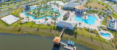 An aerial view of a resort with multiple swimming pools, a dock with boats, and a large building with a dome roof.