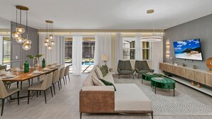 A modern living room with a dining area, a sofa, and a TV. - Last Minute Disney Getaway! Luxury Villa with Private Pool. Book Now! #39946 (Orlando)