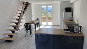 A modern kitchen with a wooden staircase, a dining area with chairs, and a view through glass doors. - Cosy ALL NEW cottage with swimming pool- (Tanneron)