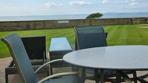 Une terrasse extérieure avec une table et des chaises, un mur en pierre et une vue sur la mer.