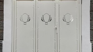 A set of three white doors with a decorative emblem, set within an arched entrance against a stone wall. - Apartment at 500 meters from the sea (Monopoli)