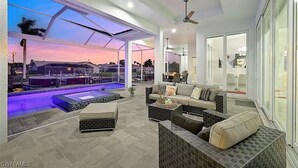 Een moderne buitenruimte met een zwembad, zitplaatsen en een overdekt terras.
