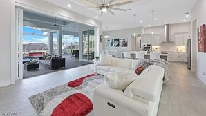 Een moderne woonkamer met een witte bank, een rood-wit kleed en een plafondventilator.