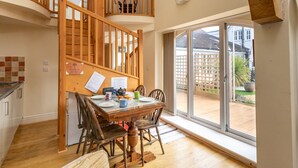 Ein Essbereich mit einer Holztreppe, einem für vier Personen gedeckten Tisch und Blick durch große Fenster nach draußen.