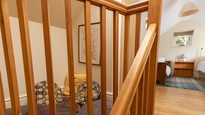 Eine Holztreppe führt zu einem Schlafzimmer mit einem Bett, einem Nachttisch und einem Fenster.