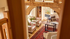 Ein gemütliches Wohnzimmer mit floral gepolsterten Sesseln, einem Couchtisch und einem roten Teppich mit Muster.