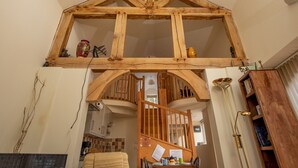 Ein Loft-Zimmer mit freiliegenden Holzbalken, einer Treppe und einer Küchenzeile.