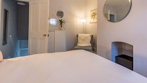 A bedroom with a bed, a chair, a small table, a mirror, and a door leading to another room. - Central cosy home 5 minutes walk from Shrewsbury - Pass the Keys (Shrewsbury)