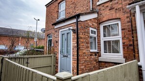 A two-story brick house with a blue door, white windows, and a wooden fence. - Central cosy home 5 minutes walk from Shrewsbury - Pass the Keys (Shrewsbury)
