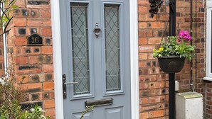 A grey door with a glass panel, a number plate '16', and a flower pot on a black stand. - Central cosy home 5 minutes walk from Shrewsbury - Pass the Keys (Shrewsbury)