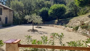 A courtyard with a stone building, a wooden fence, and a variety of plants.