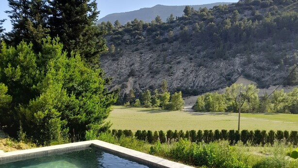 A clear swimming pool with a view of a mountainous landscape and a golf course in the background.