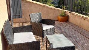 A balcony with wicker furniture, a potted plant, and a view of a mountainous landscape.