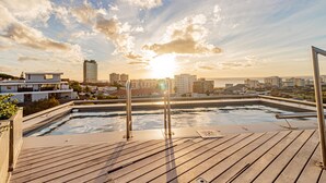 A rooftop pool with a cityscape view, including modern buildings and a sunset. - Conveniently Located Apartment in Green Point (C on S) (Cape Town)