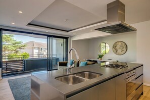 Una cocina moderna con una isla grande, electrodomésticos de acero inoxidable y vistas al exterior.