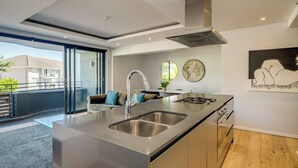 A modern kitchen with a central island, stainless steel appliances, and a large window overlooking a balcony. - Conveniently Located Apartment in Green Point (C on S) (Cape Town)