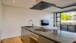 A modern kitchen with a central island, stainless steel appliances, a built-in oven, and a large window offering a view of the outdoors. - Conveniently Located Apartment in Green Point (C on S) (Cape Town)