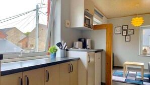 A compact kitchen with a window, a microwave, a coffee maker, and a small plant on the counter. - Résidence vallée de la Meuse 2 - Blaimont (Blaimont)
