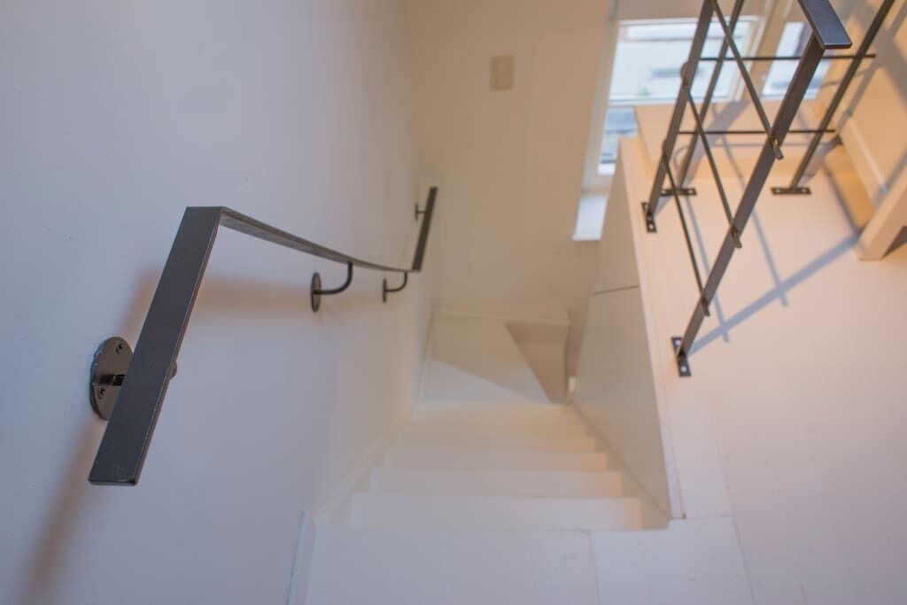Una escalera con barandilla de metal y una lámpara fijada a la pared.