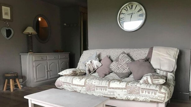 A living room with a patterned sofa, a white coffee table, a clock on the wall, and a cabinet.